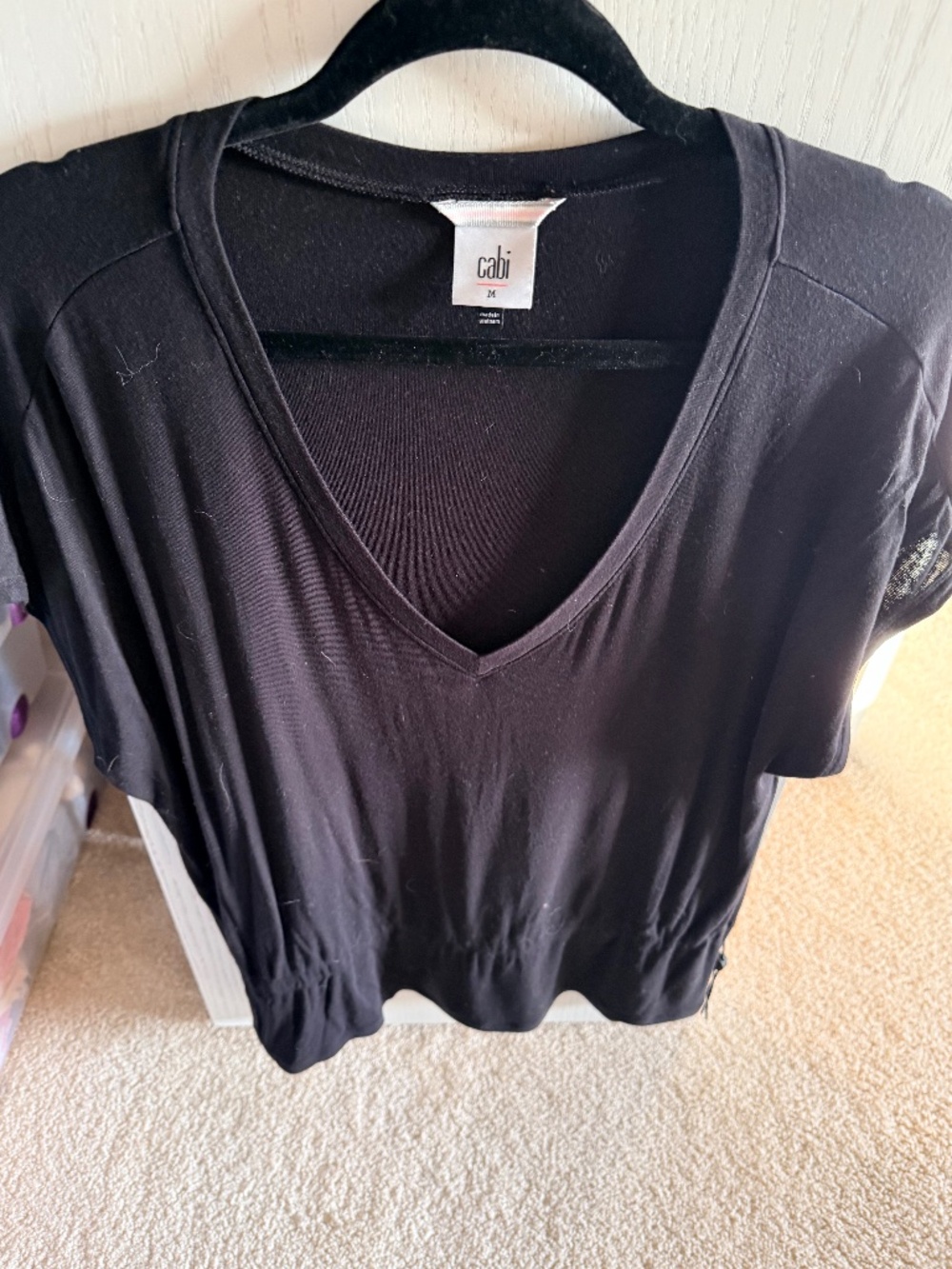 This is a black Cabi V-neck top with short sleeves and a cinched hem.